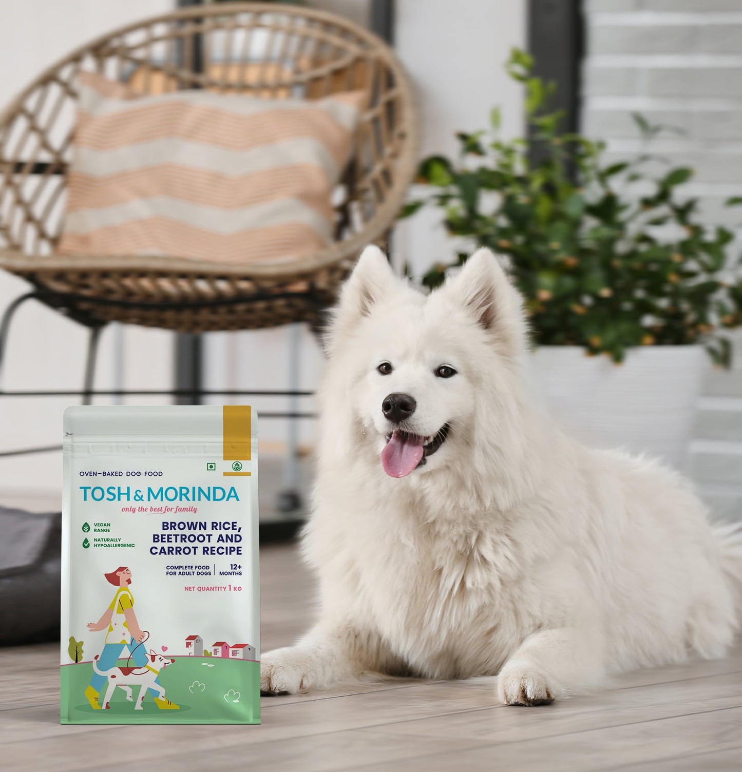 A handsome white dog sitting beside a pack of Tosh & Morinda's Brown Rice, Beetroot, and Carrot baked dog food recipe.